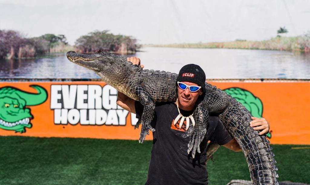 man holding alligator on shoulders during a live alligator show at our miami gator park