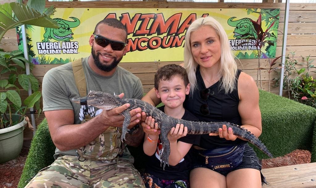 A family joyfully holding a baby alligator at an Animal Encounters event at Everglades Holiday Park